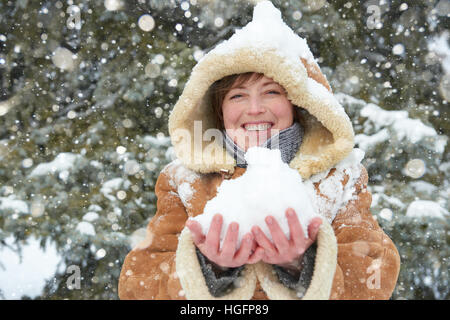 schöne Frau Spiel mit Schnee im Winter im Freien, verschneite Tannen im Wald, trägt einen Lammfell-Mantel Stockfoto