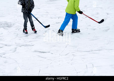 Eine Gruppe von Kindern auf der Eisbahn außerhalb im Winter Eishockey zu spielen. Stockfoto