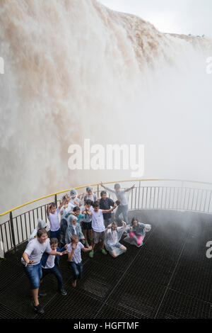 Kinder posieren für Gruppenfoto unten Iguazu Wasserfälle von der brasilianischen Seite, Iguazu National Park, Brasilien, Südamerika Stockfoto