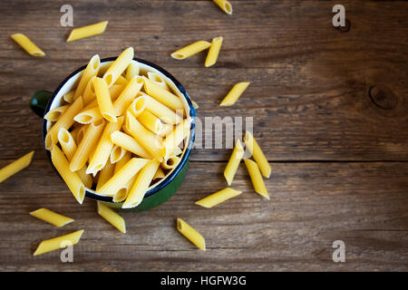 Ungekocht rohe italienische Penne-Nudeln in Metall Becher - gesunde Zutat zum Kochen Stockfoto