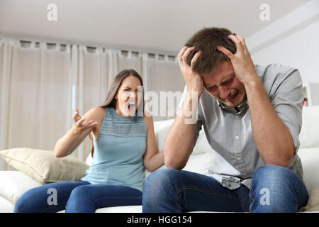 Paar streiten. Frau schreien zu ihrem verzweifelten Mann sitzt auf einer Couch im Wohnzimmer zu Hause Stockfoto