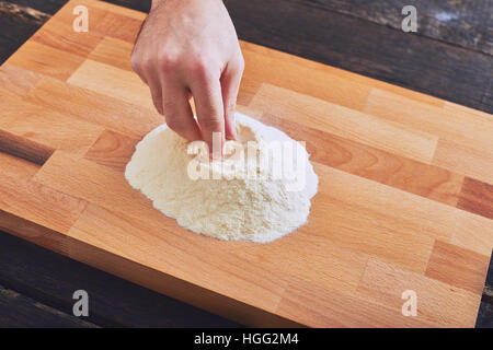 Männliche Hand Zubereitung Mehl auf Tisch Stockfoto