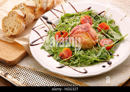 Gegrillter Mozzarellakäse eingewickelt in Schinken mit Rucola Stockfoto