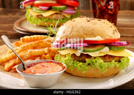Frische leckere Burger mit Pommes und Getränk auf Holztisch Stockfoto