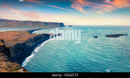 Bunte Sommer Sonnenuntergang am Kirkjufjara Strand. Abends Blick auf Reynisdrangar Klippen von Halbinsel Dyrhólaey. Süd-Island. Stockfoto