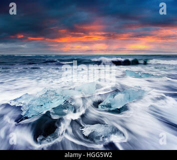 Umspült von den Wellen am Strand von Jökulsárlón Eisblöcke. Dramatische Sommer Sonnenaufgang im Vatnajökull-Nationalpark, Südost-Island. Stockfoto