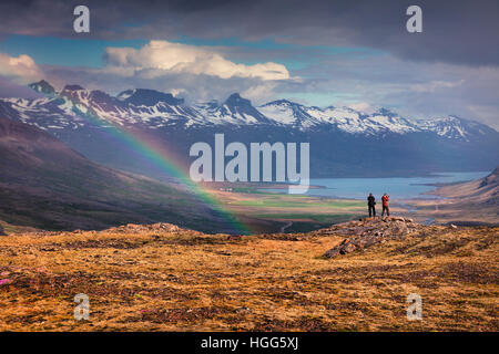 Zwei Fotografen nimmt Bild in einem leichten Regen und Regenbogen in den isländischen Bergen. Bunte Sommermorgen in der Island. Stockfoto