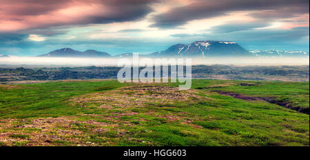 Typische isländische Landschaft mit nebligen Bergen am Horizont. Bunte Sommer Sonnenaufgang in der Nähe der Myvatn See gelegen, Island, Europa. Künstlerischer Stil Stockfoto