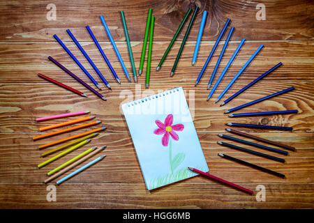 Zeichnung einer Blume Arbeitsmappe mit Farbstiften herum auf dem Holztisch Stockfoto