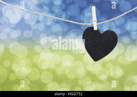 Black Heart auf Hanfseil auf abstrakten bunten Bokeh Hintergrund aufgehängt und haben textfreiraum Text verwalten, was, den Sie wollen. Stockfoto