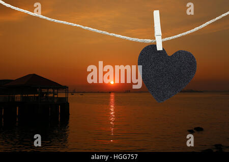 Black Heart auf Hanfseil auf Ansicht Sonnenuntergang Hintergrund aufgehängt und haben textfreiraum Text verwalten, was, den Sie wollen. Stockfoto