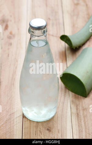 Aloe Vera Gelee in Glas-Flaschen in der Nähe von Aloe Vera Pflanze auf Holztisch, Konzept der gesunden und Bio-Lebensmittel. Stockfoto