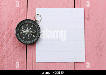 Kompass und Hinweis Papier auf dem rosa Holzboden, Konzept der Reisen und trekking. Stockfoto