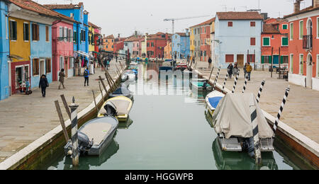 Kanal mit Booten und gesäumt von bunten Häusern und Geschäften in Burano, Venedig Italien Stockfoto