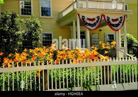 FITZWILLIAM, NEW HAMPSHIRE: Orange Tag Lilien, ein Lattenzaun und dem Eintrag Portikus drapiert mit patriotischen Bunting in der Stadtbibliothek Stockfoto