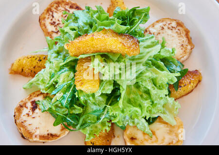 Salat mit Rucola Blätter mit Gebackener Käse und Orangenscheiben auf einem Esstisch Stockfoto