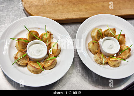 Gebratene Knödel mit saurer Sahne-Sauce in Küche des Restaurants Stockfoto