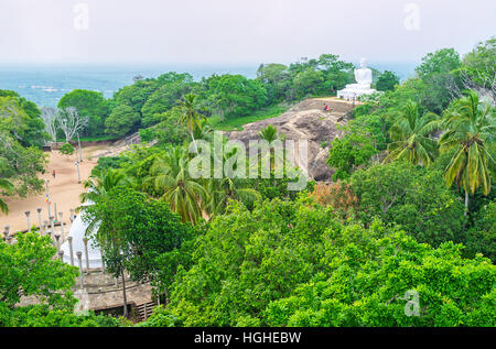 Die malerischen grünen Hänge der Mihintale Tempel mit riesigen Buddha-Statue unter dem Garten, Sri Lanka. Stockfoto