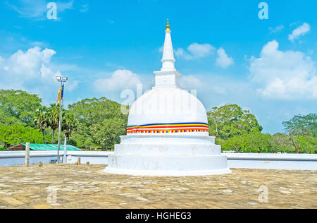 Die kleinen Stupa in Ecke des Komplexes Ruwanwelisaya mit dem bunten Gürtel in den Farben der buddhistischen Flagge, Anuradhapura, Sri Lanka. Stockfoto