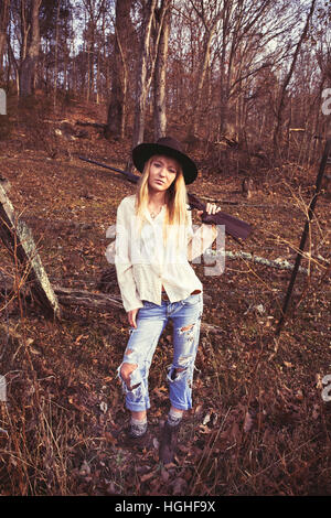 Junge blonde Frau im Wald mit einer Pistole Stockfoto