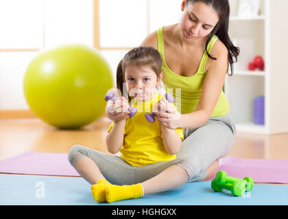 Junge attraktive Frau und ihr Kind Mädchen trainieren mit Hanteln Stockfoto