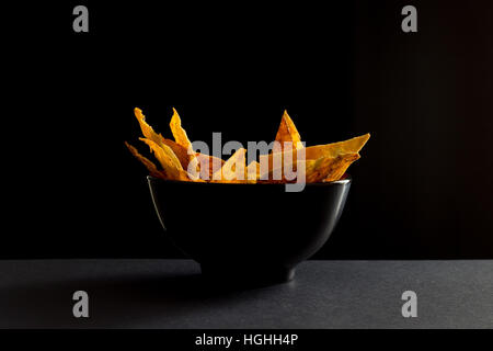 Gebratene würzige mexikanische Tortilla-chips in schwarzer Schale Stockfoto