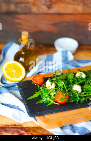 Frische italienische Caprese-Salat mit Mozzarella und Tomaten, Rucola auf dunkle Platte Stockfoto