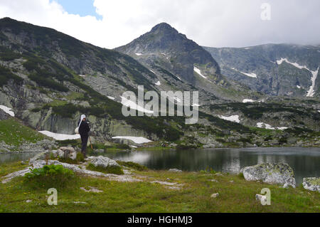 Junger Mann spielen auf Dudelsack durch eines der sieben heiligen Seen im Rila-Gebirge, Bulgarien Stockfoto