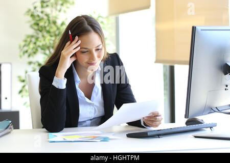 Geschäftsfrau Lesen eines Dokuments in einem Desktop im Büro sitzen Stockfoto