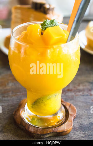 Mango Smoothie in Glas auf Holztisch Stockfoto