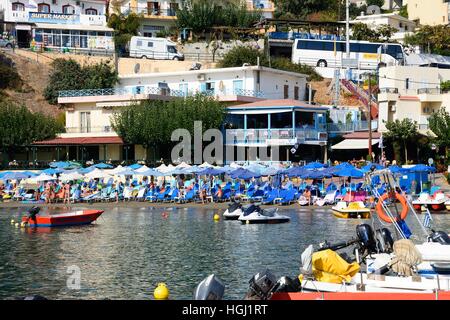 Touristen entspannen am Strand mit Booten vertäut im Hafen, Bali, Kreta, Griechenland, Europa. Stockfoto