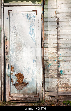 Nahaufnahme der alten Holztür mit Malerei Farbe abgeblättert. Abblätternde Farbe an der Tür des verlassenen Hauses als Vintage Holz Hintergrundtextur. Stockfoto