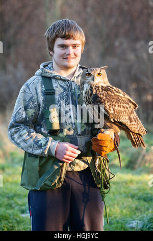 Ein junger Falkner in der Landschaft mit seinen Raubvogel, eine eurasische Adler-Eule. VEREINIGTES KÖNIGREICH. Stockfoto