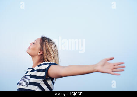 Junge Frau unter blauem Himmel frei fühlen Stockfoto