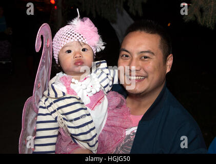 Glückliche Amerikaner asiatischer Abstammung Vater seinen kostümierten Baby Durchführung für eine Halloween trick or treat Abend. St Paul Minnesota MN USA Stockfoto