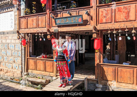 Lijiang, China - 14. November 2016: Junge chinesische paar gekleidet mit Trachtenmode halten Sie die Hände vor einem alten Gebäude im Sh Stockfoto