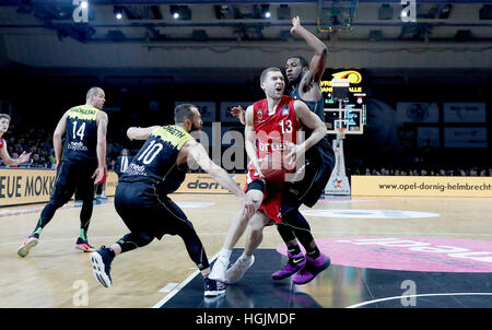 Bamberger Janis Strelnieks (in rot) durchbricht die Medi-Verteidigung während der Basketball-Match zwischen Medi Bayreuth und Brose Baskets Bamberg in Oberfranken-Halle in Bayreuth, Deutschland, 22. Januar 2017. Foto: Daniel Löb/dpa Stockfoto