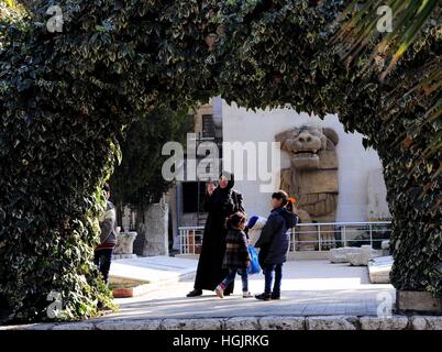 Damaskus, Syrien. 22. Januar 2017. Eine syrische Frau kommt mit ihren zwei Kindern in der Nähe eine Skulptur des Löwen im Garten des nationalen Museum von Damaskus, Syrien.  Die islamische Staat Gruppe hat mehr wertvolle Denkmäler abgerissen in Syriens antiken Palmyra, einen Monat nach von Regierungstruppen, Rückeroberung des Landes Antiquitäten Chef sagte Freitag. Die Vereinten Nationen am Freitag führte Verurteilung dieser Angriffe fordern die Zerstörung einer "Kriegsverbrechen" und "kulturellen Säuberung". Bildnachweis: Ammar Safarjalani/Xinhua/Alamy Live-Nachrichten Stockfoto