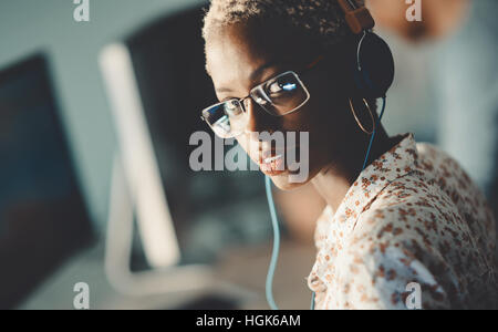 Afroamerikanische Frau mit Brille arbeiten am Schreibtisch im Büro Stockfoto