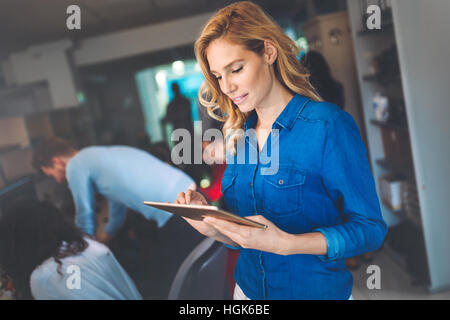 Schöne blonde Geschäftsfrau mit Tablet im modernen Büro Stockfoto
