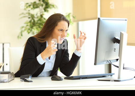 Wütend Geschäftsfrau Anzug mit einem Desktopcomputer auf Linie neben ein Fenster im Büro Stockfoto