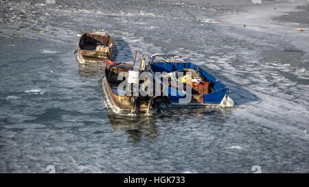 Donau, Serbien - drei verankerten Fischerboote gefangen in einem gefrorenen Fluss Stockfoto