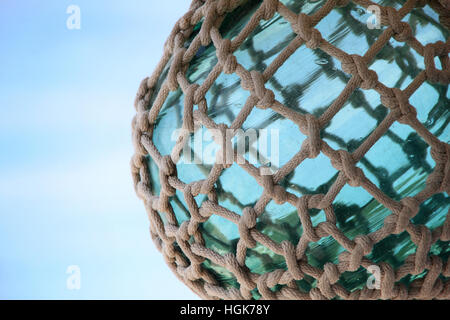 Türkis-grüne Meer Glaskugel mit nautischen Seil & Knoten vor einem blauen Himmel gefesselt. Stockfoto