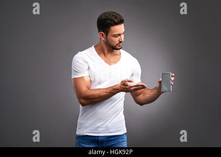 Ein zuversichtlich hübscher junger Mann mit seinem Handy auf die Kamera. Stockfoto