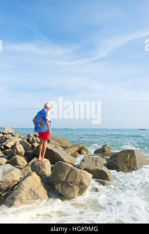 Senior-Mann mit Blick auf das Meer trägt ein blaues Hawaii-Hemd Stockfoto