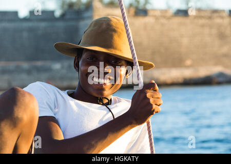 Junger Mann auf einer Dhau vor der Festung, Mozambique Island (Ilha de Mocambique), Mosambik Stockfoto