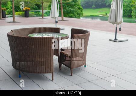 Rattan Sofa und Tisch inmitten eines Gartens Stockfoto