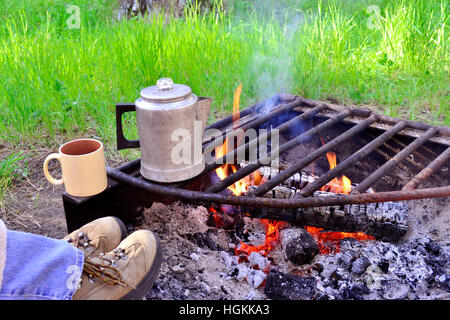 Füße auf ein Lagerfeuer warten auf den Kaffee Perk Stockfoto