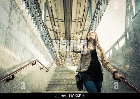 Junge Frau am Bahnhof winken verabschieden beim Treppen hinuntersteigen Stockfoto