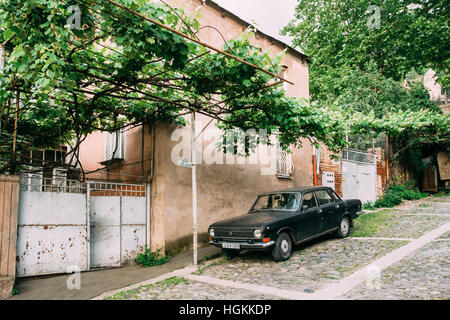 Tiflis, Georgien - 20. Mai 2016: Die Ansicht der geparkten schwarzen Wolga GAZ, Retro-Rarität-Auto in der Nähe das Private Wohnhaus unter Rebe Baldachin auf Kopfsteinpflaster Stockfoto